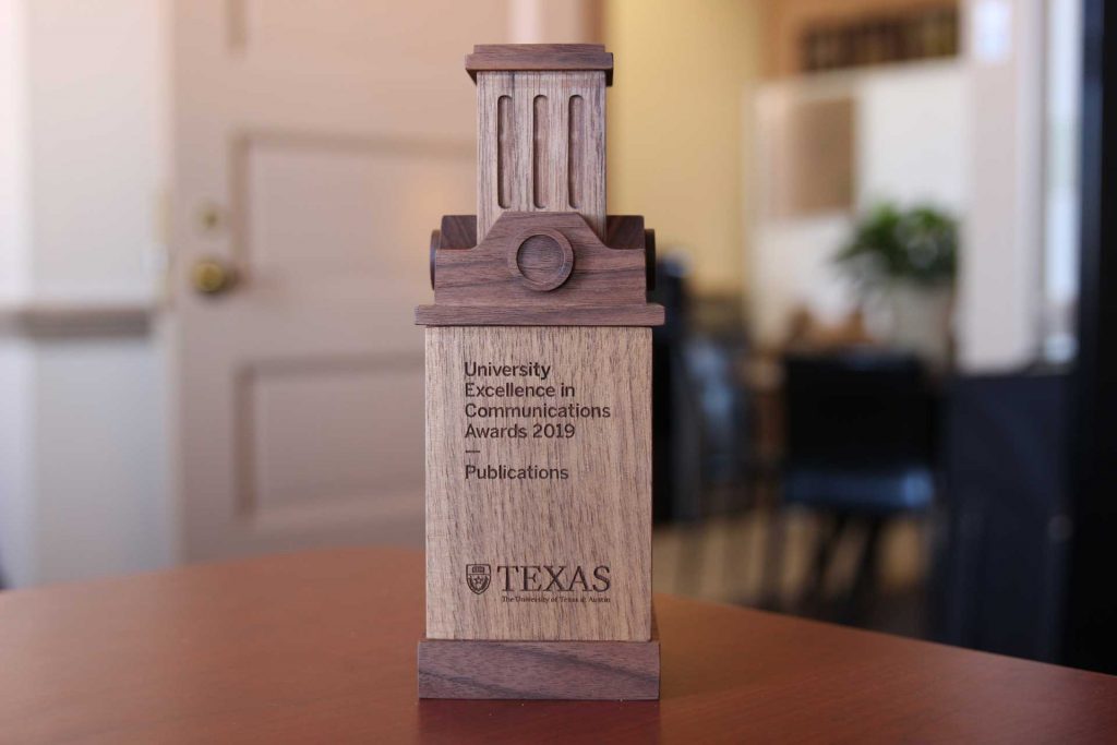 Wooden statue of University Excellence in Communications Awards 2019, Publications with office setting in background.