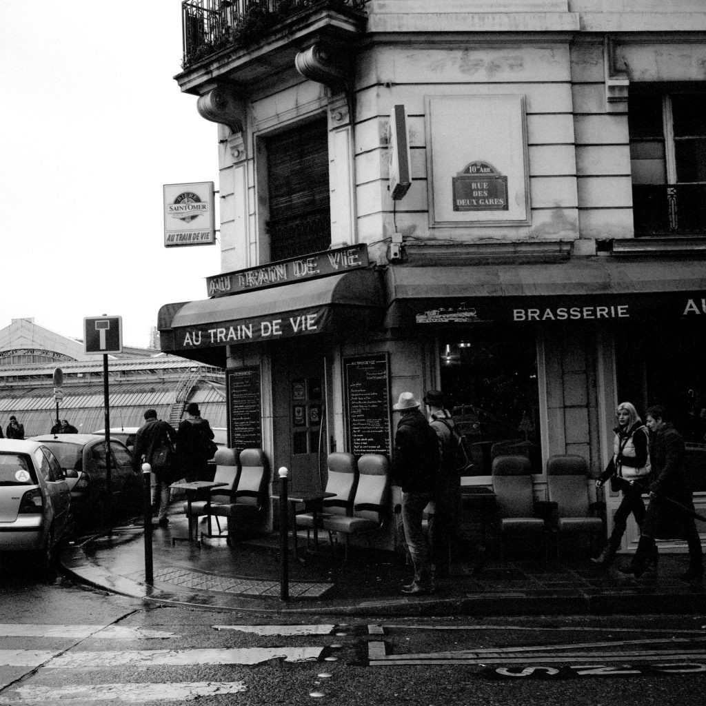 Black and white photo of a rainy street, Au Train de Vie, Paris, France.