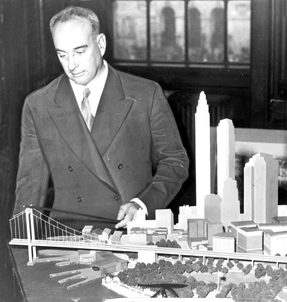 Robert Moses (1888-1981), one of the most powerful urban planners in New York of the mid-20th century, with a model of his proposed Battery Bridge. Ultimately he was forced to settle for a tunnel connecting Brooklyn to Lower Manhattan.