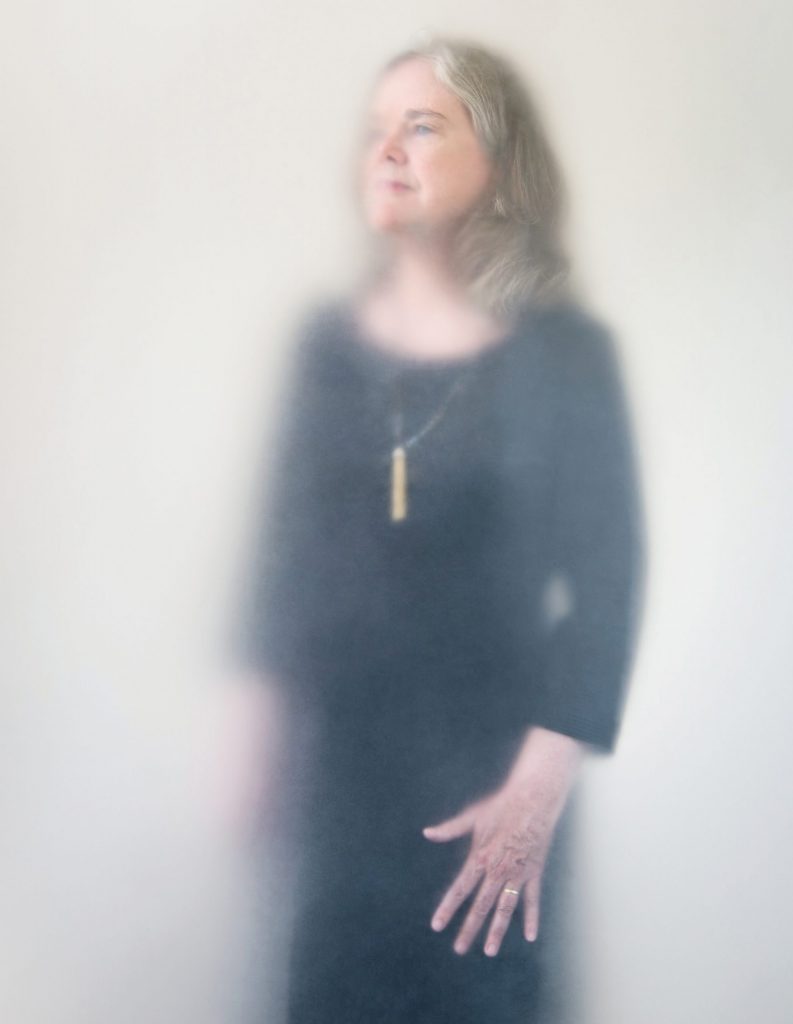 Artistic photo of a woman looking off to the left through a cloudy vellum.