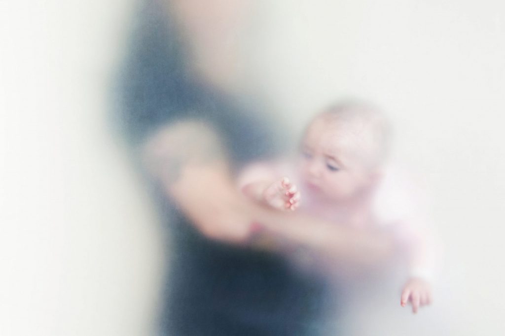 Artistic photo of a mother holding her baby through a cloudy vellum.