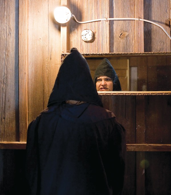 man facing mirror in black pointed hood