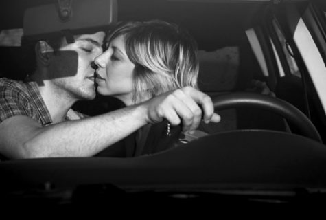 black and white photo of man and woman kissing in a car