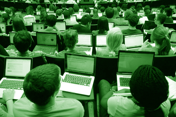 green colored photo of students using laptops in lecture hall