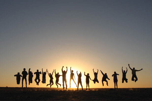 People jumping up in the air silhouetted by the setting sun in Botswana. Photo courtesy of Botswana Study Abroad Program.