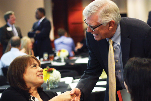 Dean Randy Diehl shakes hands with a guest at an event.