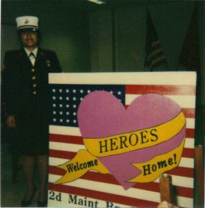 Parrish next to a welcoming sign she painted for troops coming home from Desert Storm.