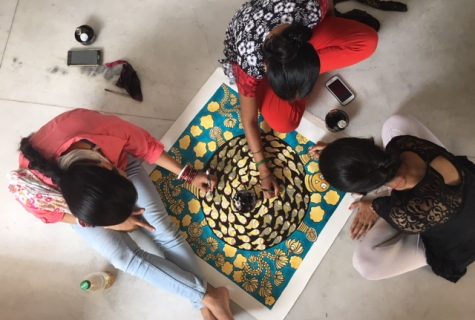 Aerial view of three artisans work together on a painting