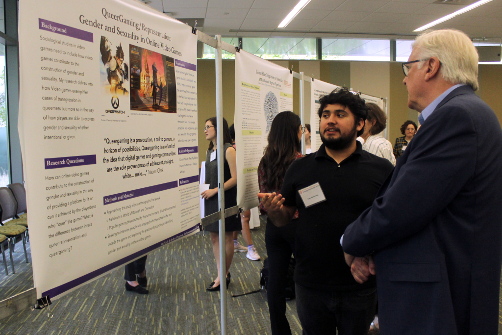 Luke Hernandez  explains his research poster to Randy Diehl. 