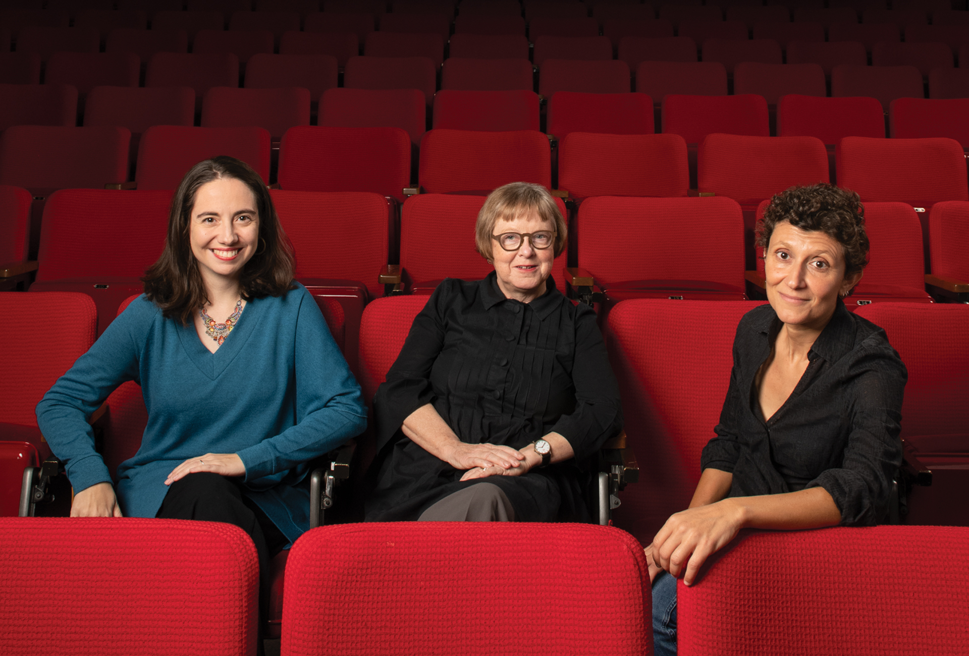 Three women sitting in an empty movie theater