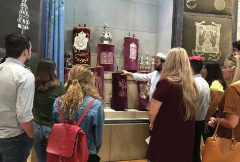 A group gathered around a collection of royal crowns and artifacts