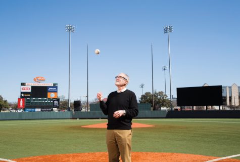 Larry Carver stands on the pitcher's mound of the UFCU Disch-Faulk field and tosses a baseball up in the air.