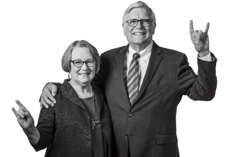 Randy Diehl stands with his arm around Mary, they're both smiling and giving a Hook Em sign with one hand.