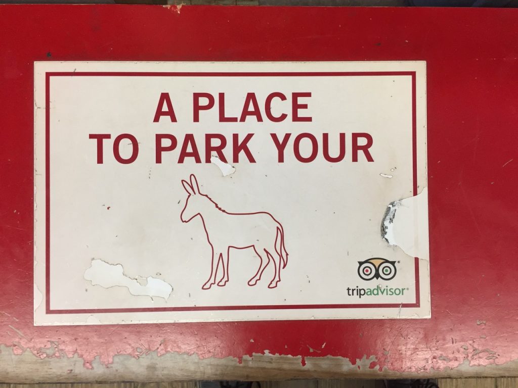 Red bench sign with "A place to park your" with a donkey symbol.
