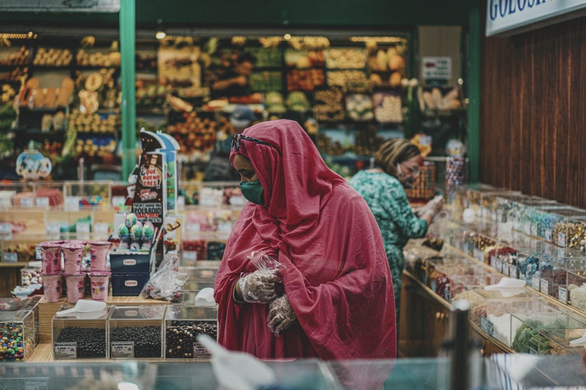 Woman with masks and gloves in candy shop