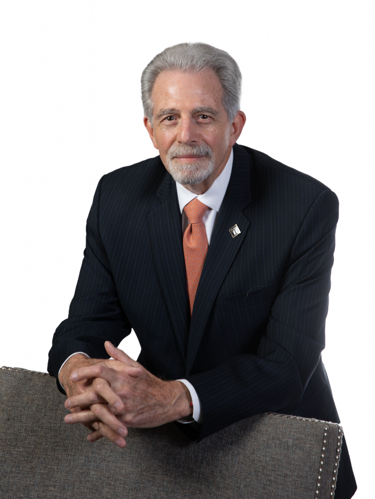 Michael Stoff leans against the back of a chair with his hands clasped in front of him.