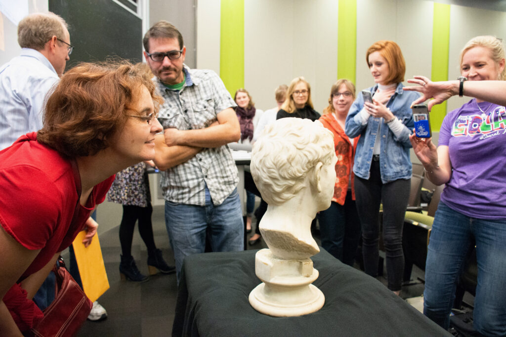 White marble Roman bust found at Austin Goodwill being viewed up close by University of Texas at Austin students